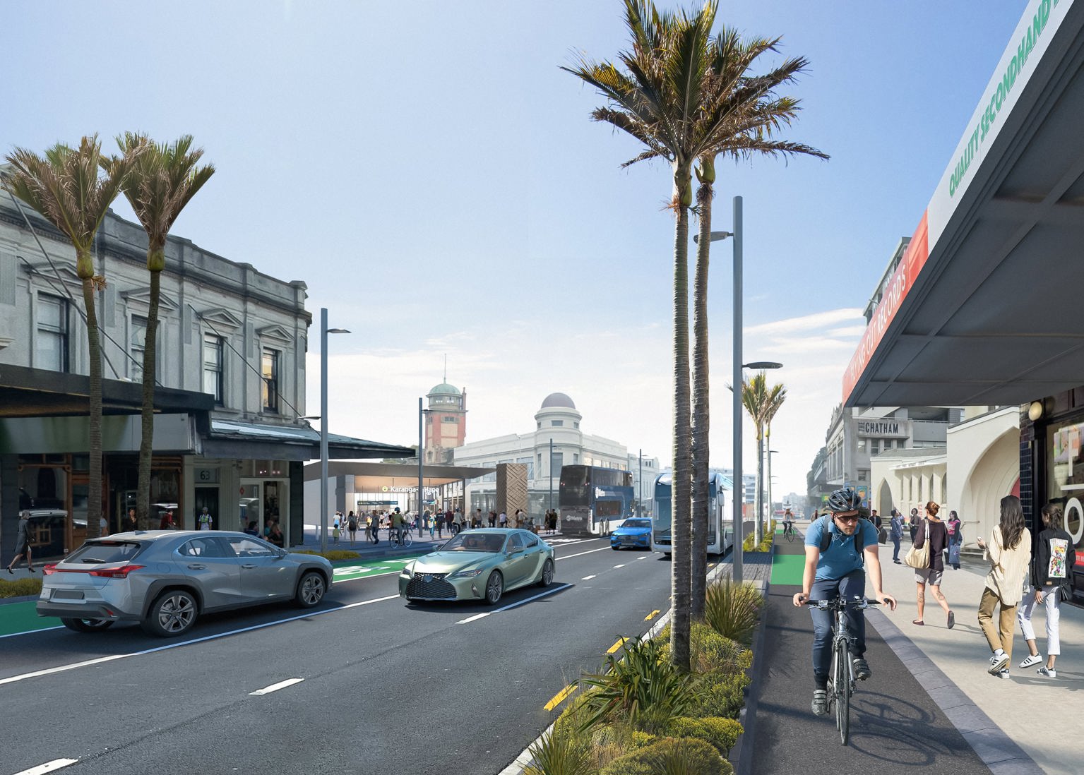 A man wearing a helmet rides his bike on a separated cycle lane on a street lined with mixed retail businesses. The street is landscaped with palm trees and shrubs.